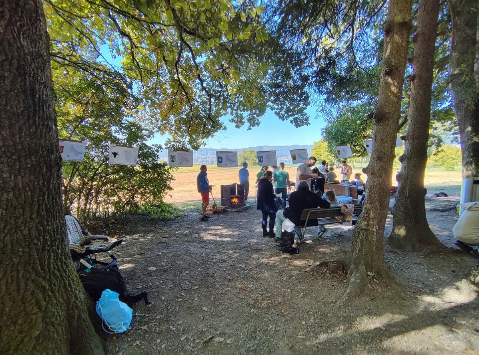 Familien und Begleitpersonen unter den Bäumen beim Grill und der Verpflegung